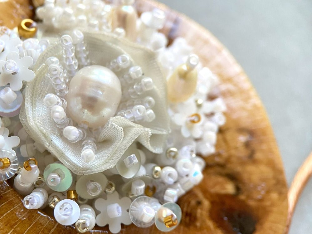 Exclusive wooden pendant with textile and beaded floral center crafted in various hues of white