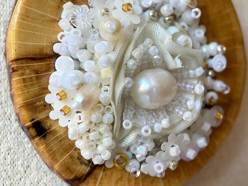 Exclusive wooden pendant with textile and beaded floral center crafted in various hues of white