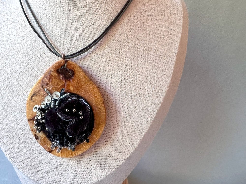 Exclusive wooden pendant with textile and volume-beaded floral inlay crafted in elegant black