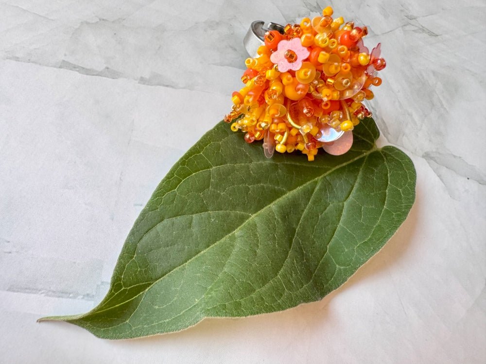 Colorful ring crafted in volume-beading technique from bright orange beads and sequins imitating a blossoming flowerbed - Ornamentico