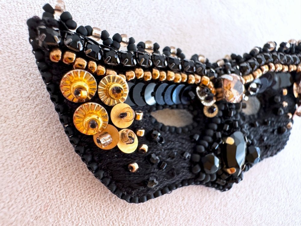 Handmade brooch in the shape of a Venetian masquerade mask crafted in black and gold from beads, sequins, rhinestones and embroidery - Ornamentico Shop