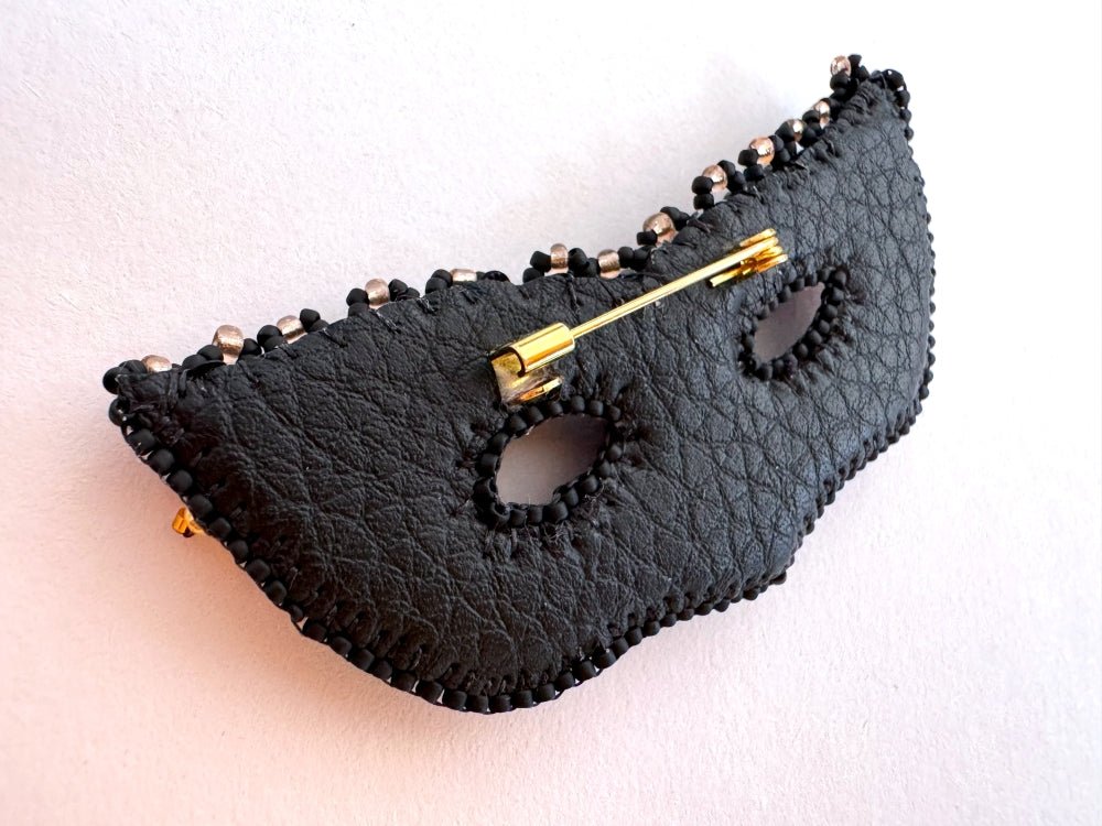 Handmade brooch in the shape of a Venetian masquerade mask crafted in black and gold from beads, sequins, rhinestones and embroidery - Ornamentico Shop