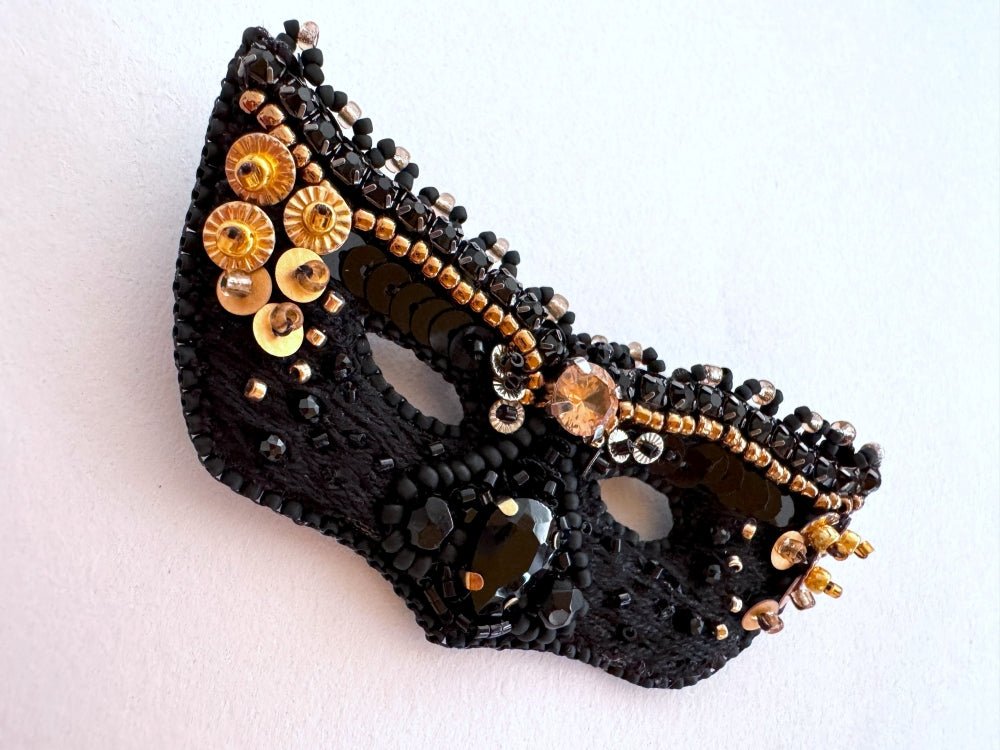 Handmade brooch in the shape of a Venetian masquerade mask crafted in black and gold from beads, sequins, rhinestones and embroidery - Ornamentico Shop