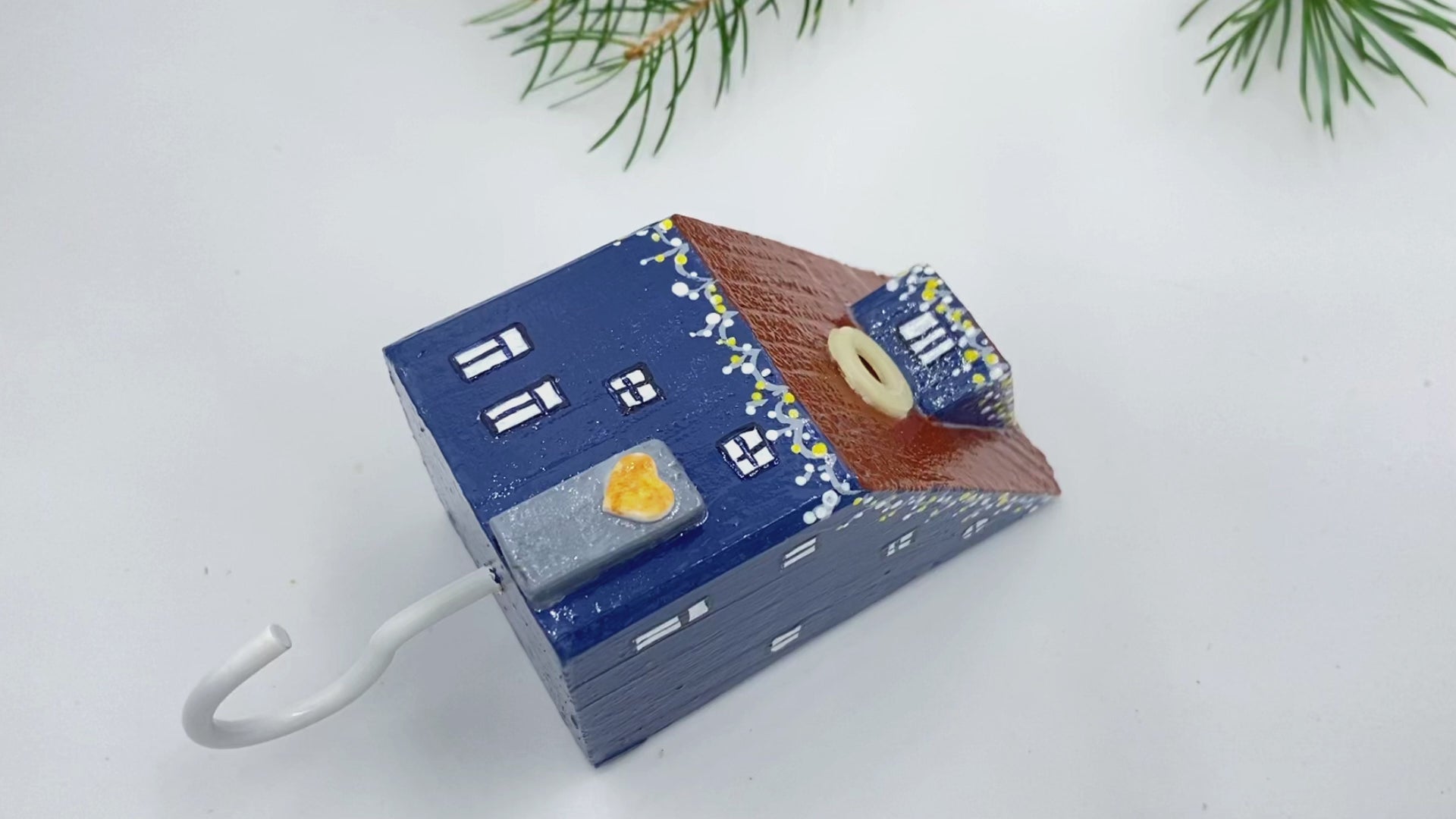 Handmade wall-mounted wooden hook in the shape of indigo blue house decorated with festive garland - Ornamentico shop