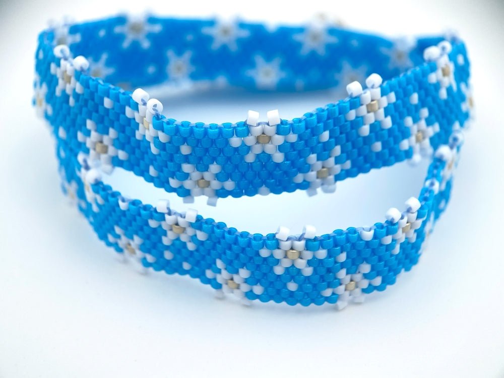 Handmade beaded bracelet featuring white snowflakes on a bright azure blue - Ornamentico shop