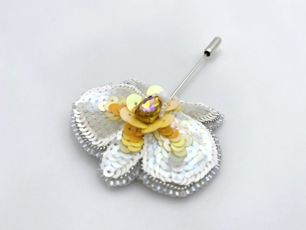 Handmade pin brooch made from rhinestone, sequins and beads in the shape of a small white orchid - Ornamentico shop
