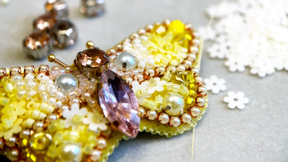 Butterfly-shaped decorative item made of beads and crystals on a light background
