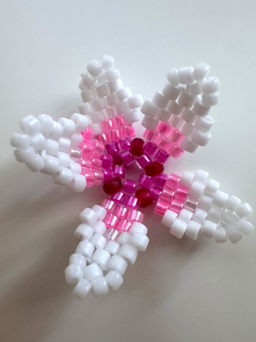 A handmade beaded cherry blossom ornament featuring white outer arms, pink middle sections, and a dark red center, crafted from Miyuki  beads on a plain light background.