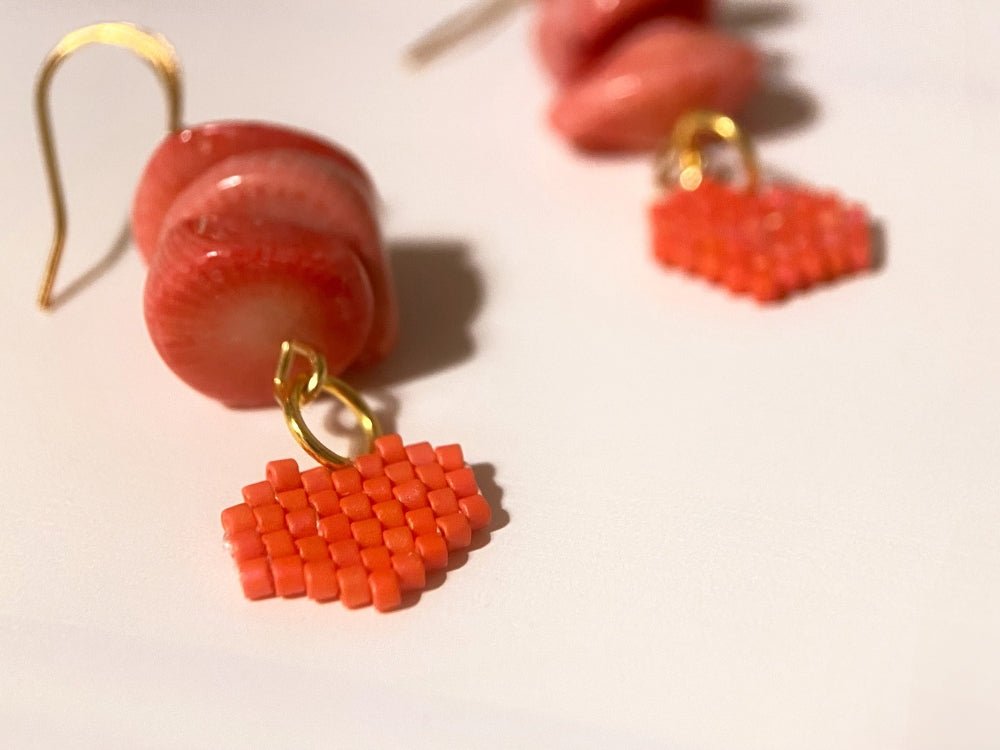 Earrings with coral chips and a small beaded charm in the shape of a heart crafted in peyote stitch technique using Miyuki Delica beads