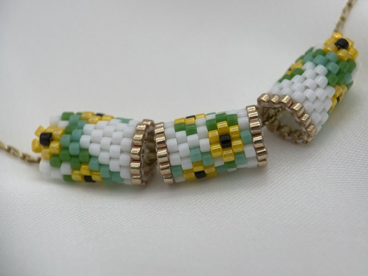 Three tubular sunflower pendant pieces made with white, yellow, green, black and gold Miyuki Delica beads
