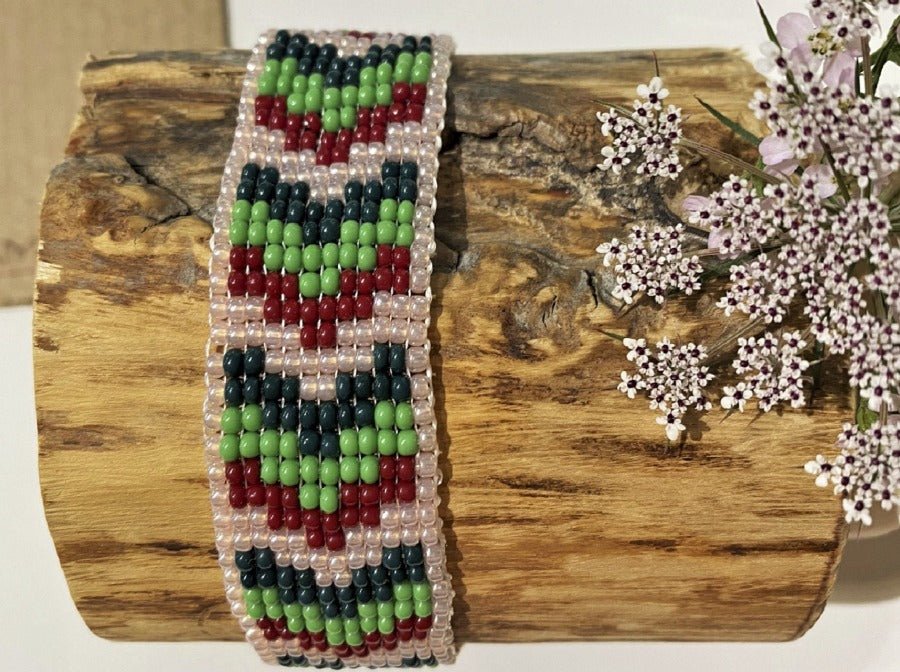Handmade bracelet made from beads crafted in weaved technique. Geometric green, white and red festive pallet.