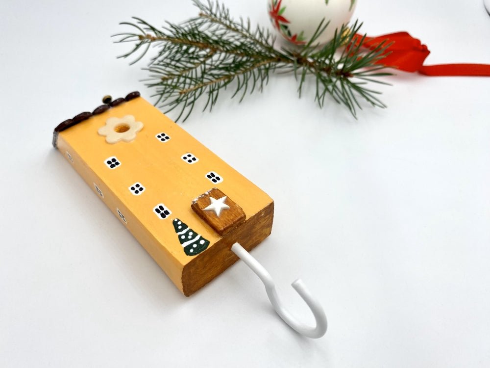 Handmade wooden hook in the shape of a pale orange house decorated for Christmas - Ornamentico shop